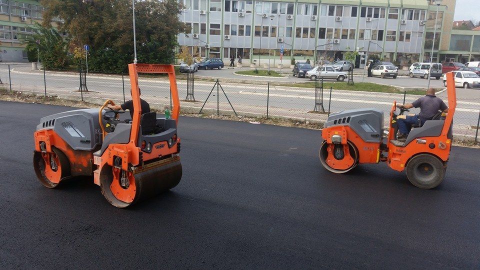 Dva valjka zbijaju novi asfalt na parkingu fabrike